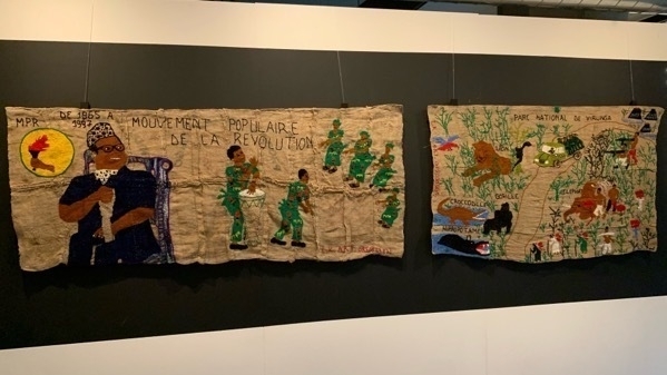 Two pieces of embroidery on burlap hanging in a gallery space. One depicts Mobutu; the other Virunga National Park.