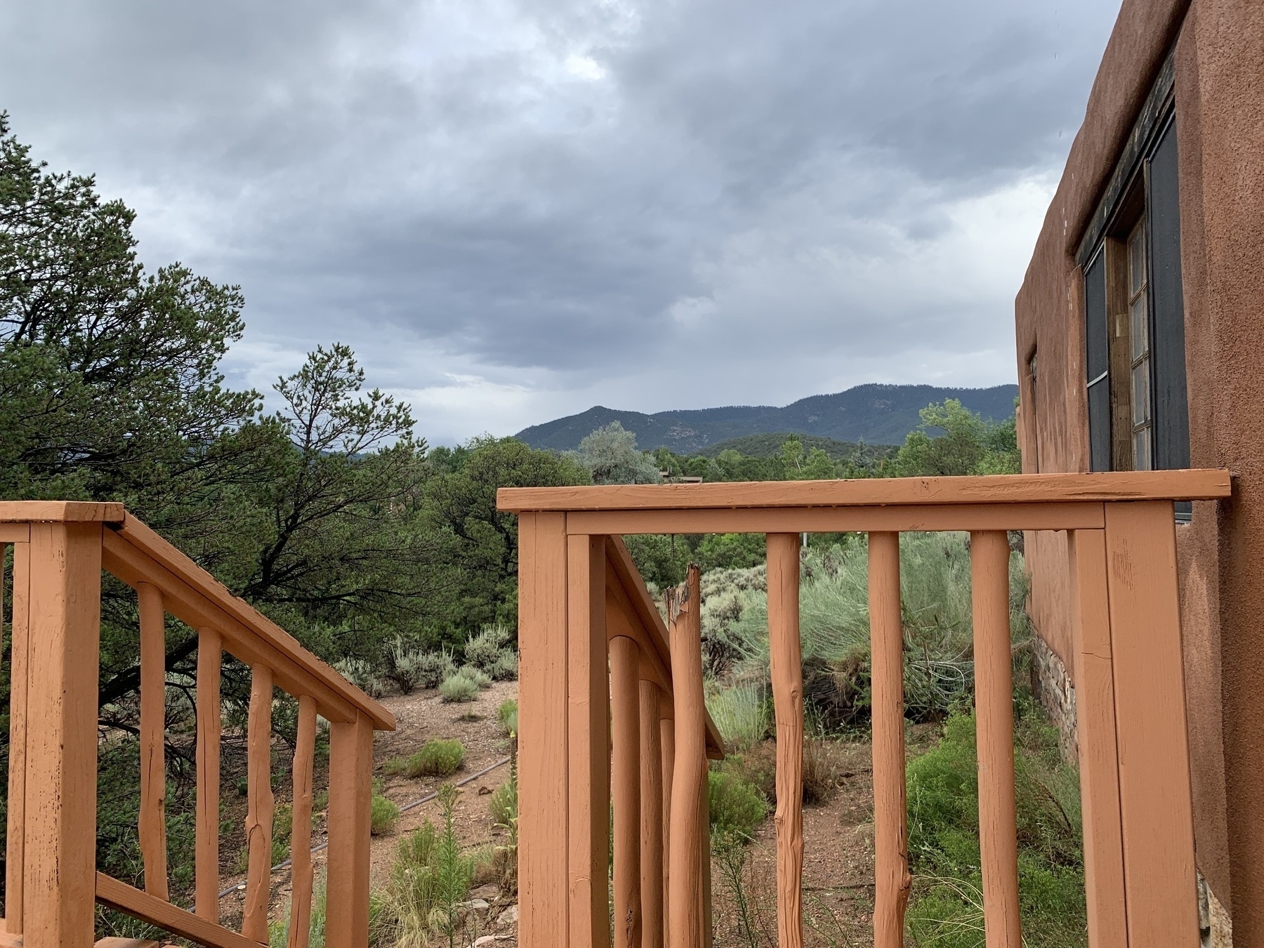 Mountains and desert landscape in the background with adobe house on right side in foreground